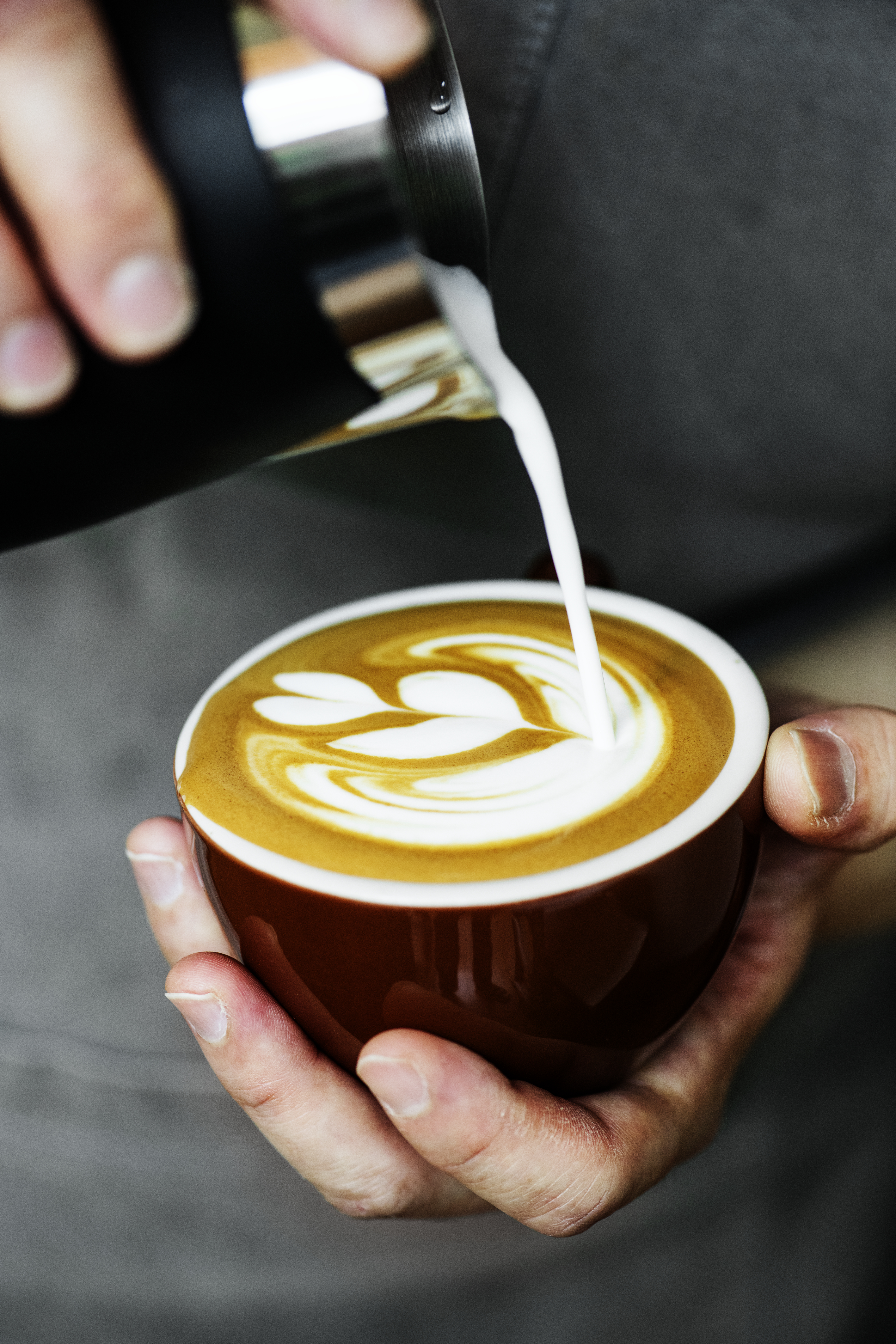 Closeup einer Barista, wie sie Latte-Art mit Milchschäum betreibt