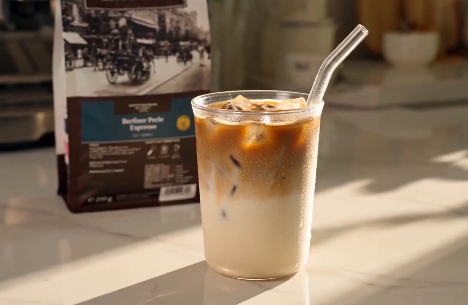 Berliner Kaffeerösterei Kaffeerezept Eiskaffee Sommer mit Espresso und Eiswürfeln Iced Latte im Becher mit Strohhalm