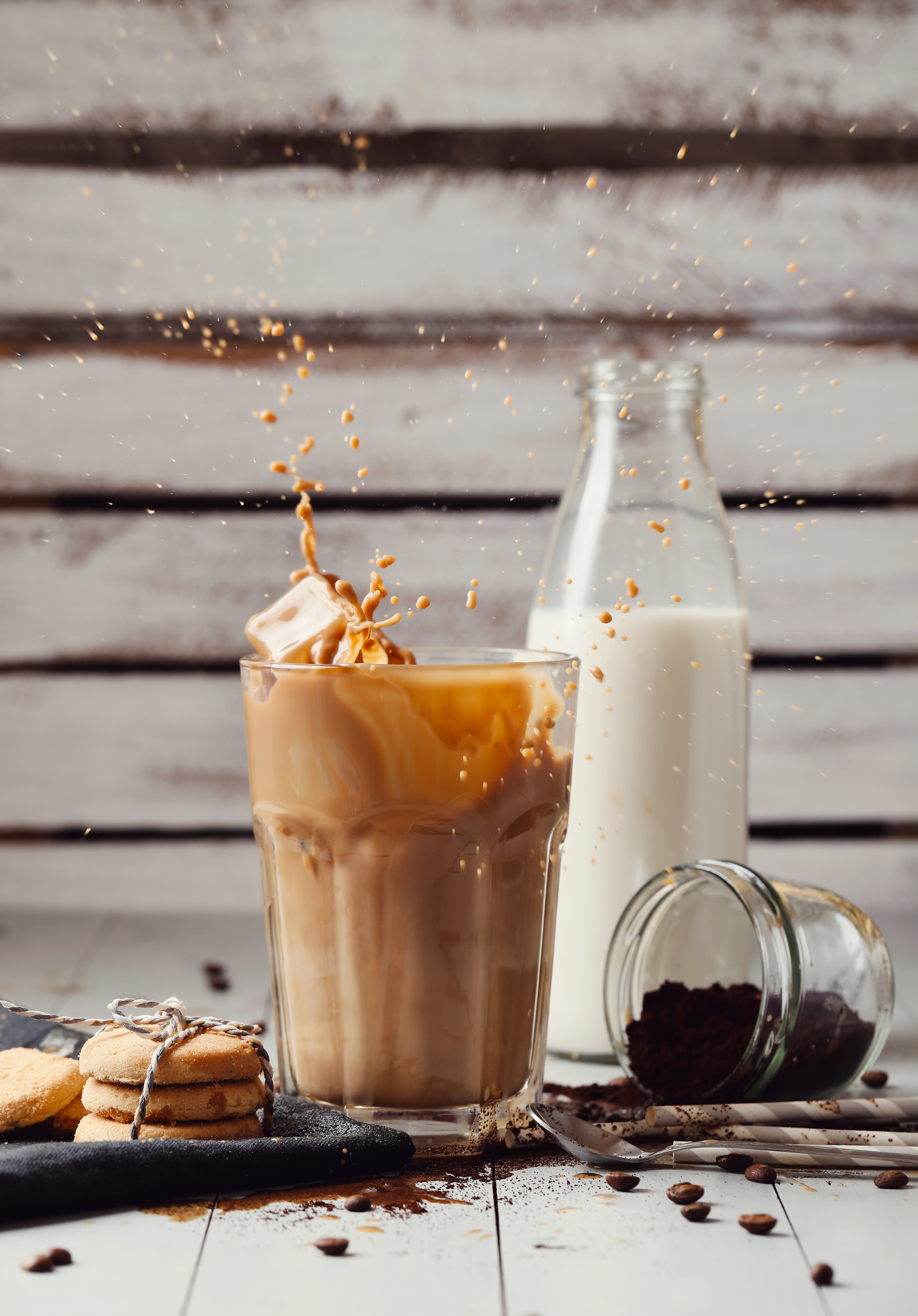 Iced Kaffee Latte mit Milch und Kaffeebohnen im Hintergrund