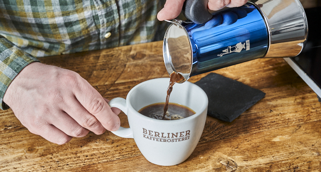 Mann schenkt Kaffee mit blauer Espresso Herdkanne von Bialetti in Kaffeetasse von der Berliner Kaffeerösterei ein