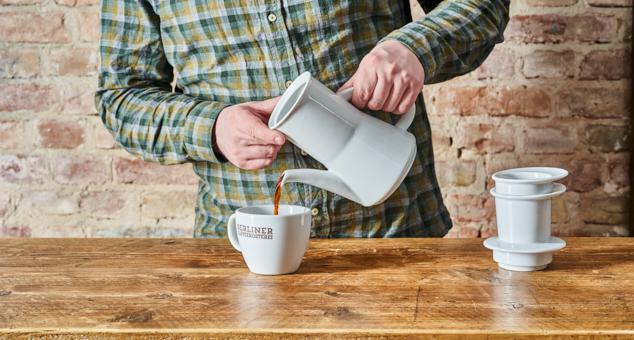 Mann gießt Kaffee mit Karlsbader Kannein Berliner Kaffeerösterei Tasse