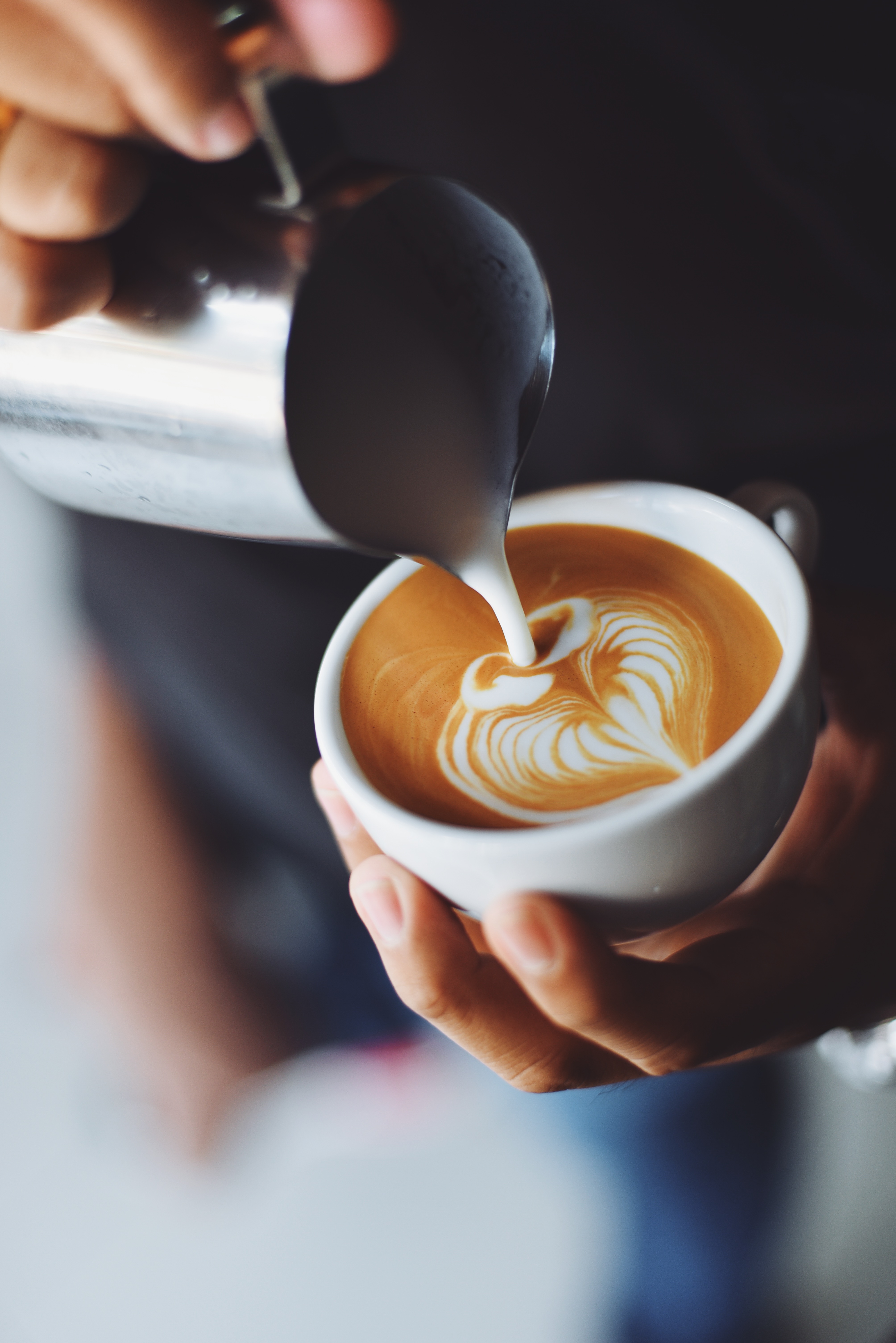 Kaffee mit Latte-Art Closeup einer Barista, wie sie Latte-Art mit Milchschäum betreibt