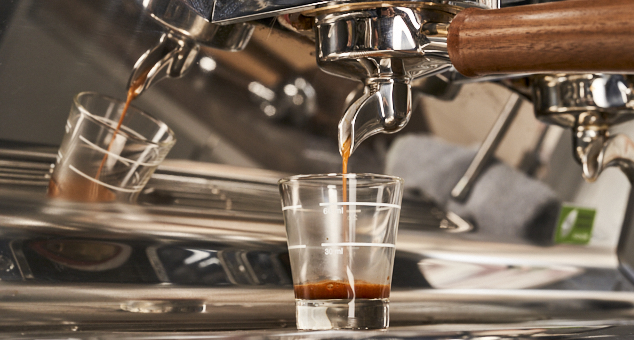 Espresso wird mithilfe von Siebträger in Shotglas extrahiert