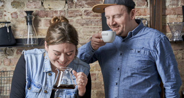 Eine Frau und ein Mann genießen in rustikalem Ambiente Handfilterkaffee