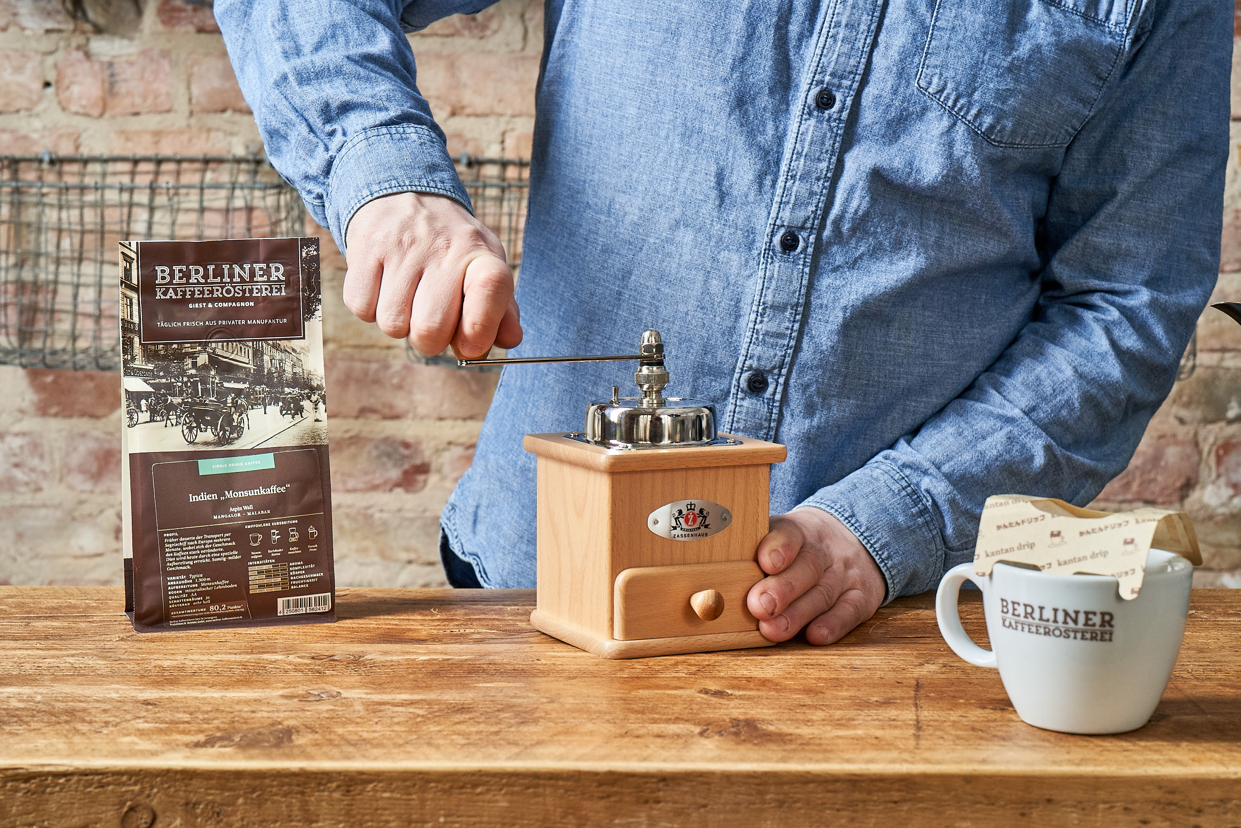 Mann benutzt klassische Handmühle zum Mahlen seines Berliner Kaffeerösterei Kaffees