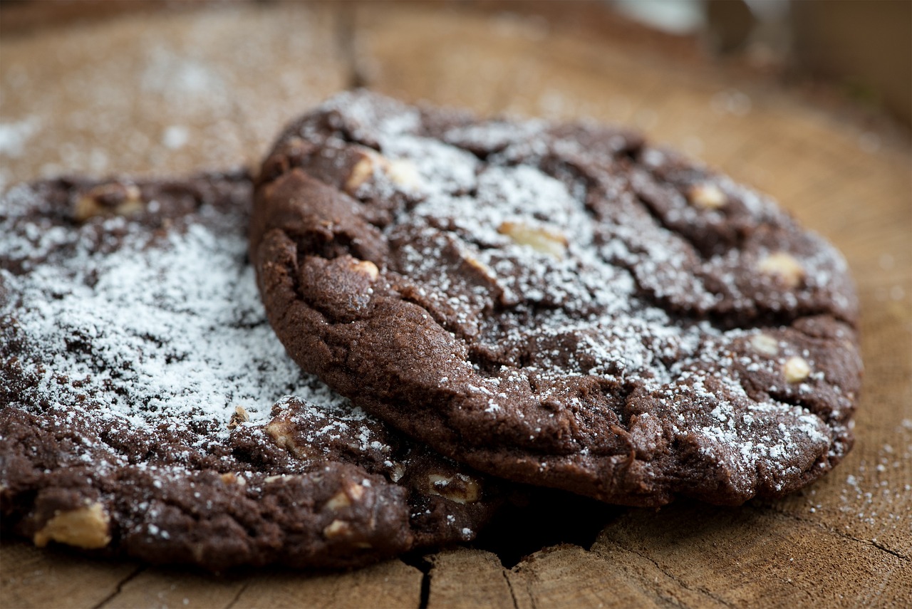 Schoko-Nuss-Cookies mit Puderzucker auf einem Holzbrett in Nahaufnahme