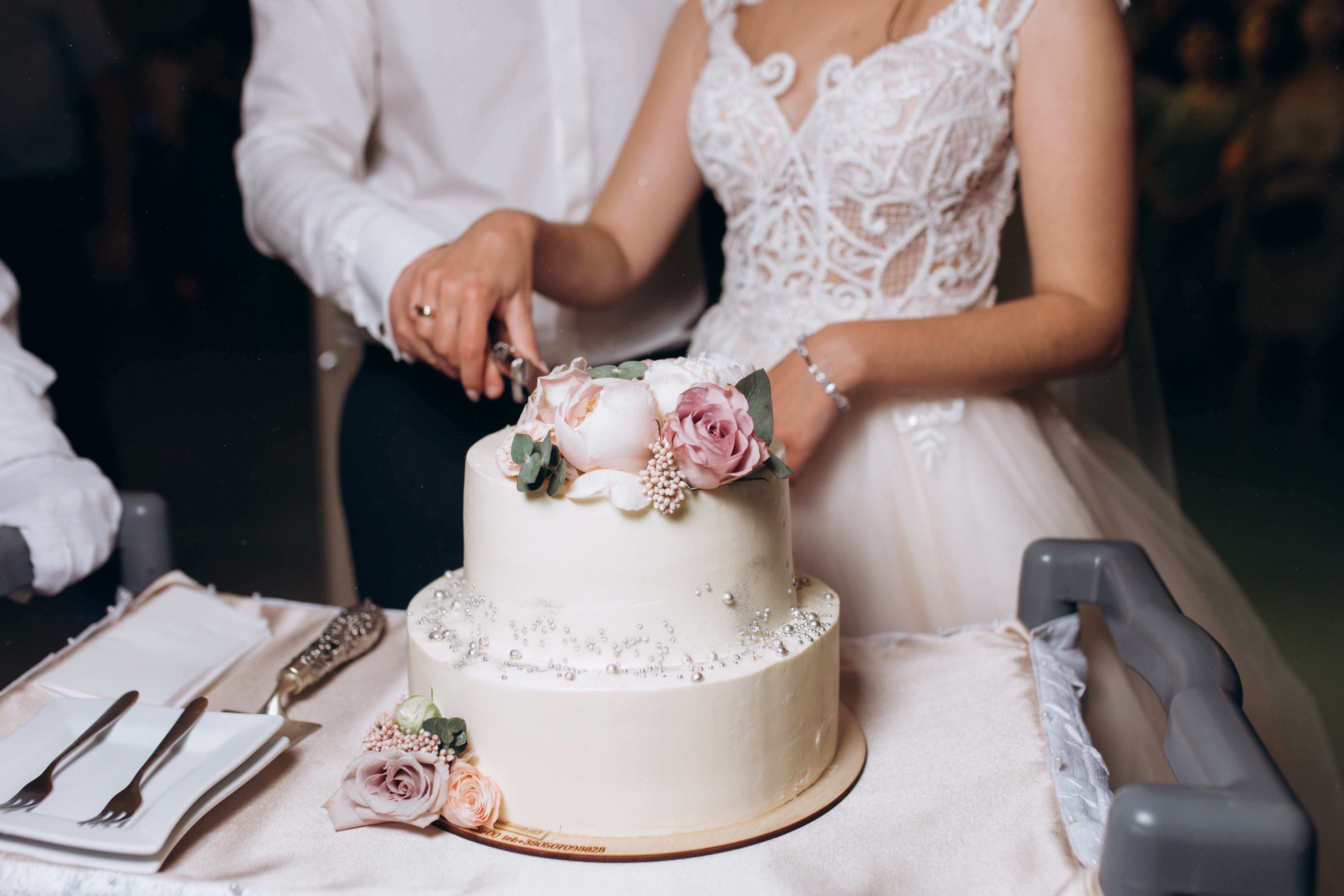bride-groom-are-cutting-decorated-with-flowers-wedding-cake