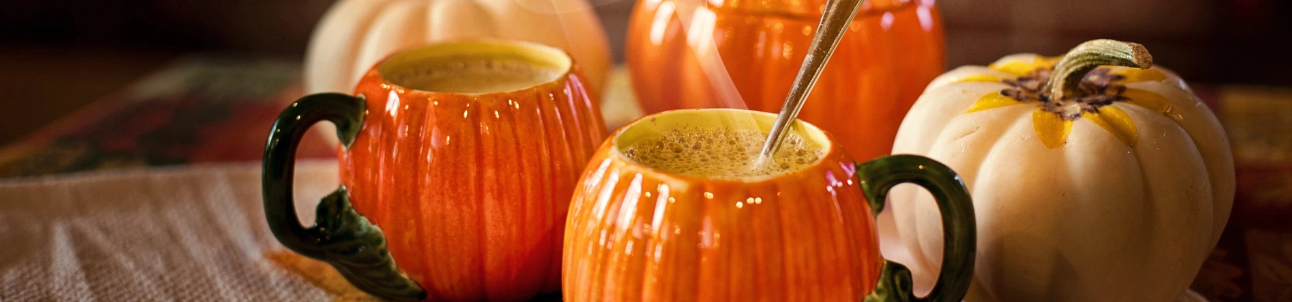 Pumpkin Spice Latte in Kürbistassen. Dampfend und lecker - Hintergrund