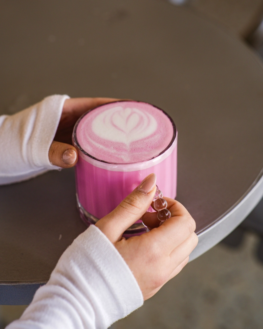 Pink Matcha Getränk in Händen mit Latte Art im Glas